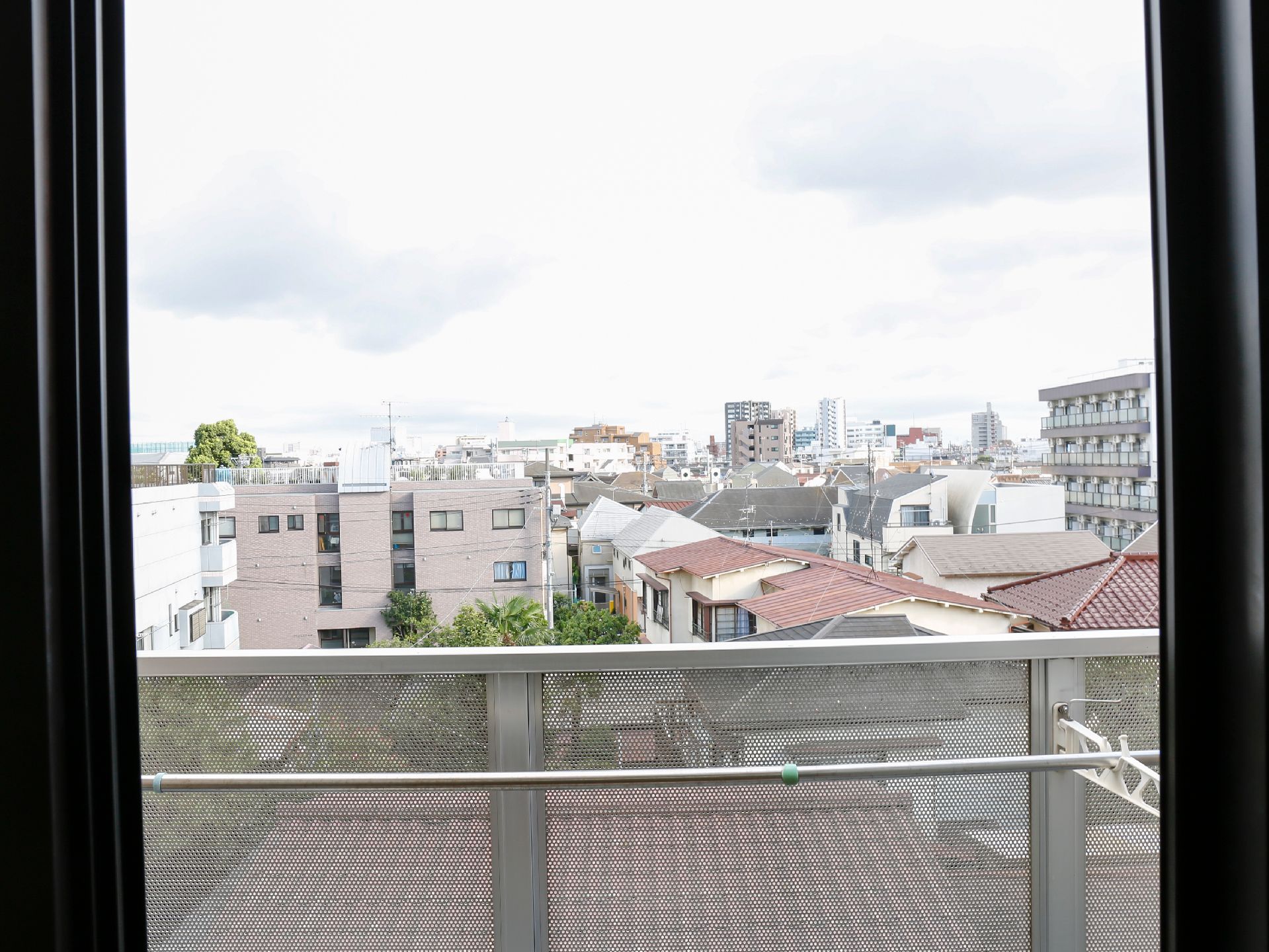窓からは施設の周囲にある一戸建ての住宅の屋根や、マンションなどの建物がみえる。窓をあけると風通しが良くなる。