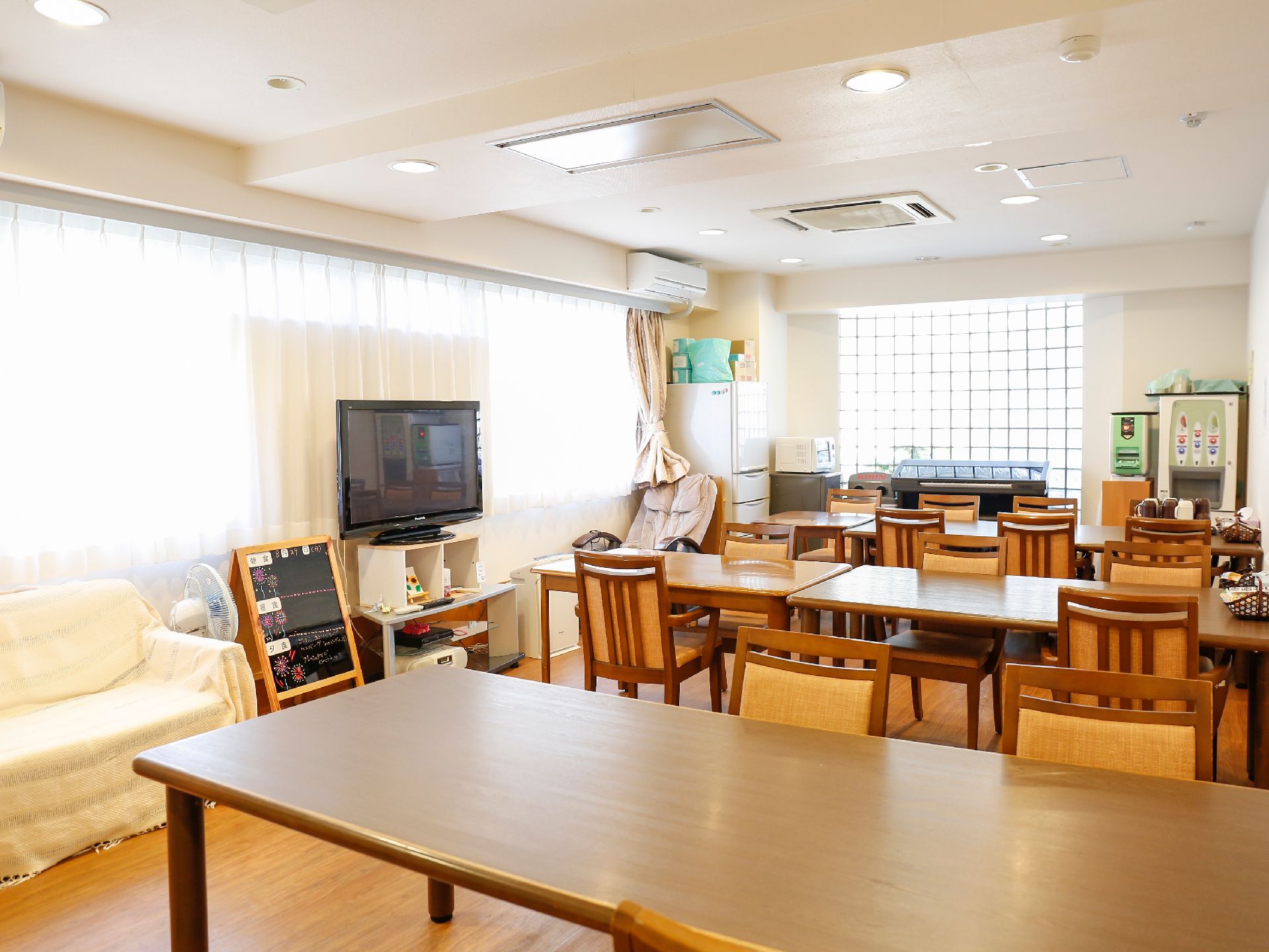 食堂は大きな窓があるので、日中は明るく過ごしやすい。テーブルやいすが数多く並べられ、テレビもある。テレビの横にはソファーも設置されている。