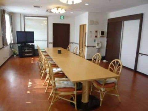入居者様が毎日お食事する食堂にはテレビが置かれている。すべての壁には手すりが付いており、ドアは引き戸のため安心して移動していただける。
