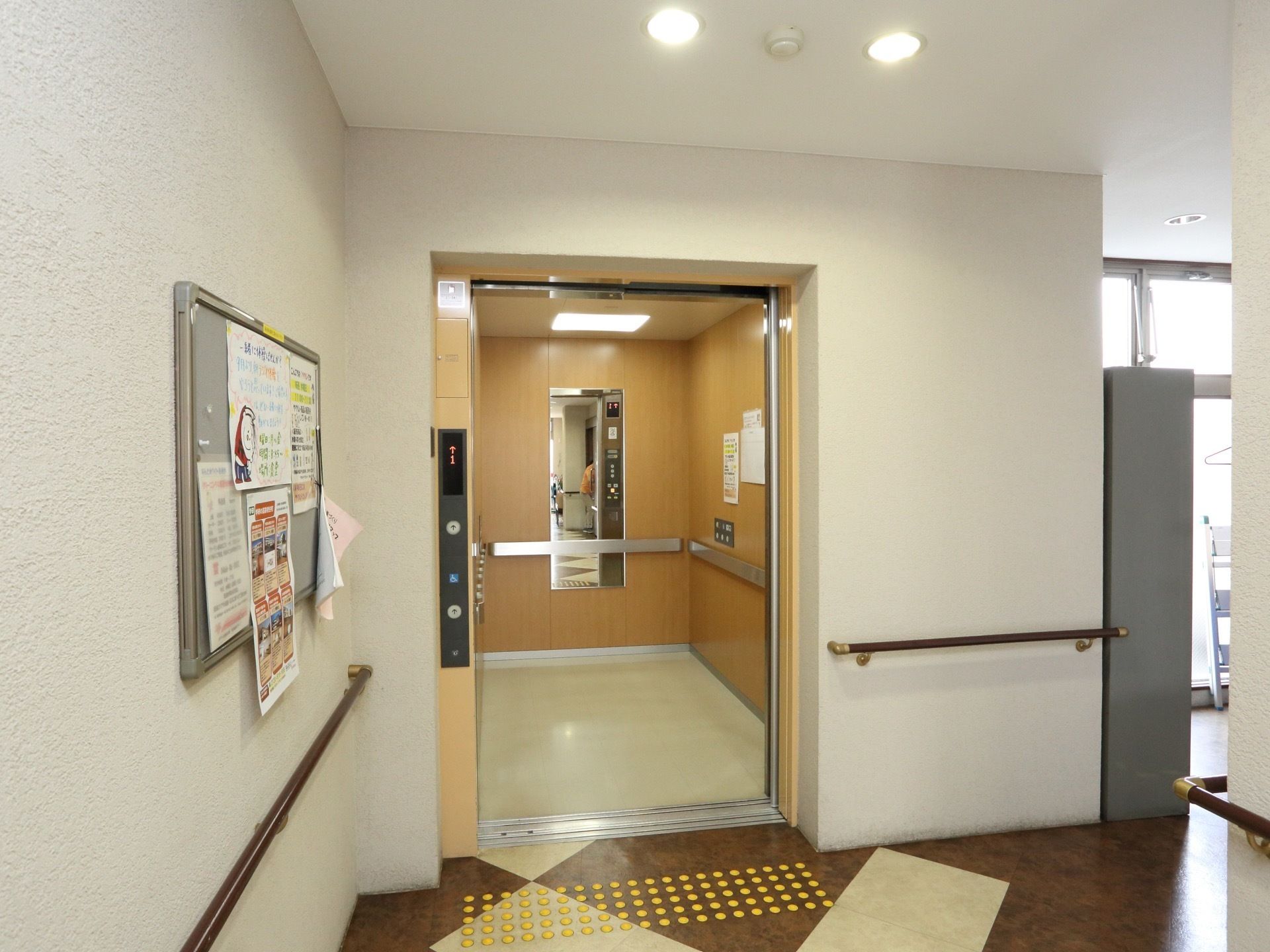 エレベーターの中は木目調の壁で、鏡を設置している。乗降ボタンは下方部に設置されている。頑丈な手すりも設置している。