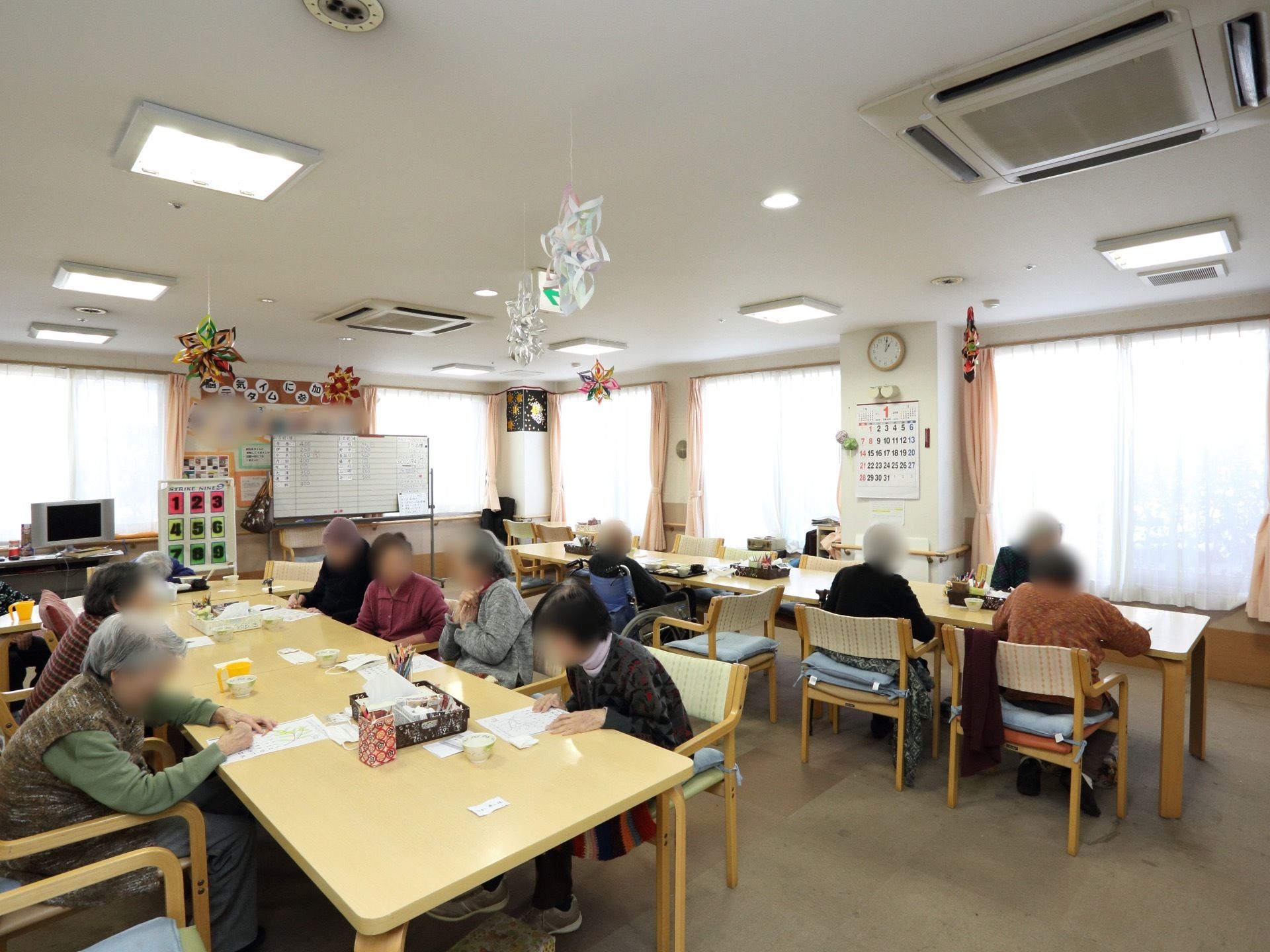 入居者様の顔が見えやすいように机を効率よく配置している。入居者様同士が雑談やレクリエーションをしている。