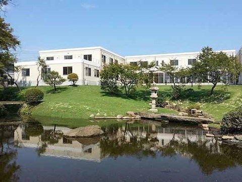 手前に大きな池が広がり、灯篭が飾られている、施設前の庭