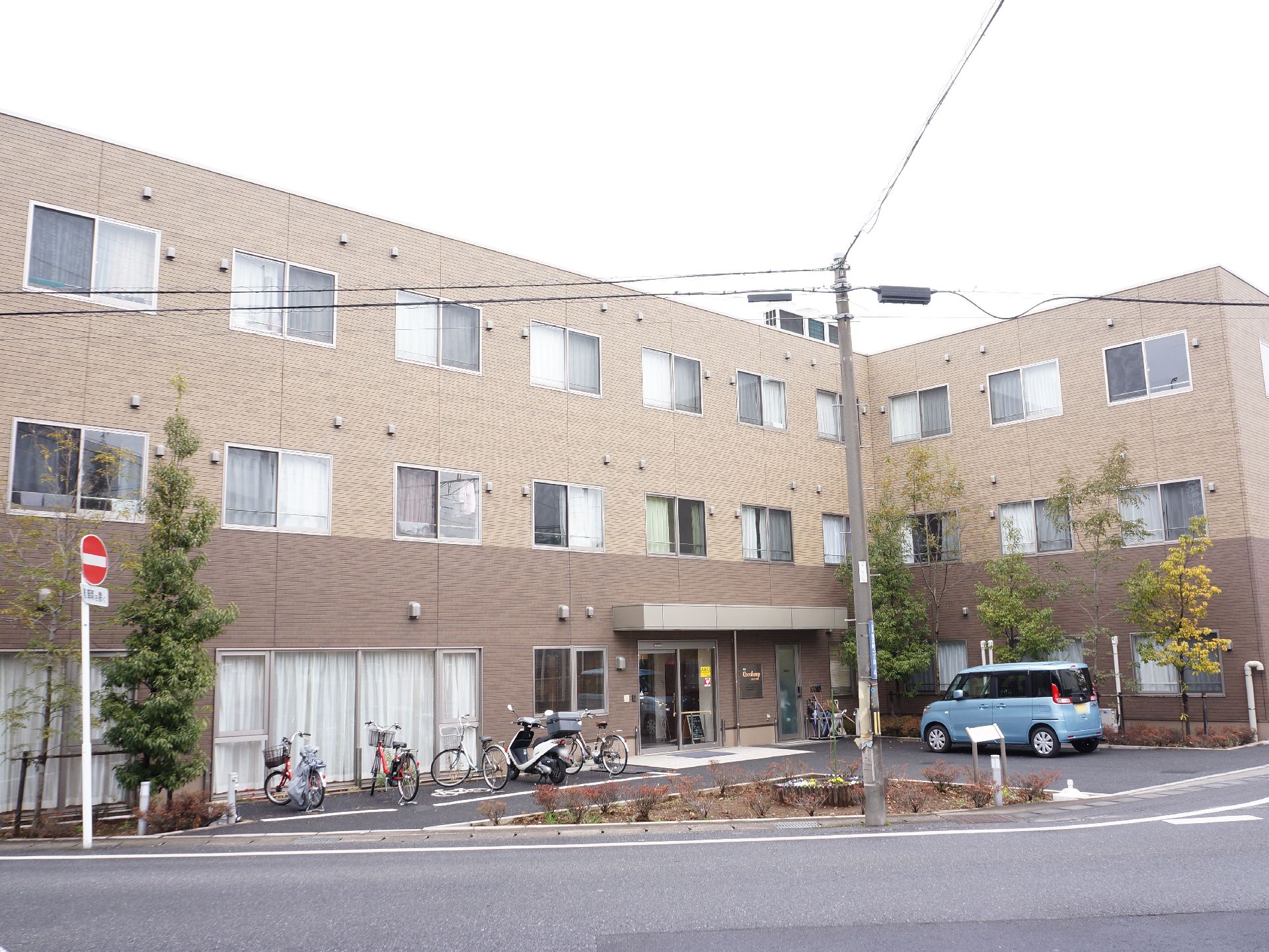 施設はしっかりした造りの3階建ての建物で、入口前には自転車をとめるスペースや車をとめるスペースがある。