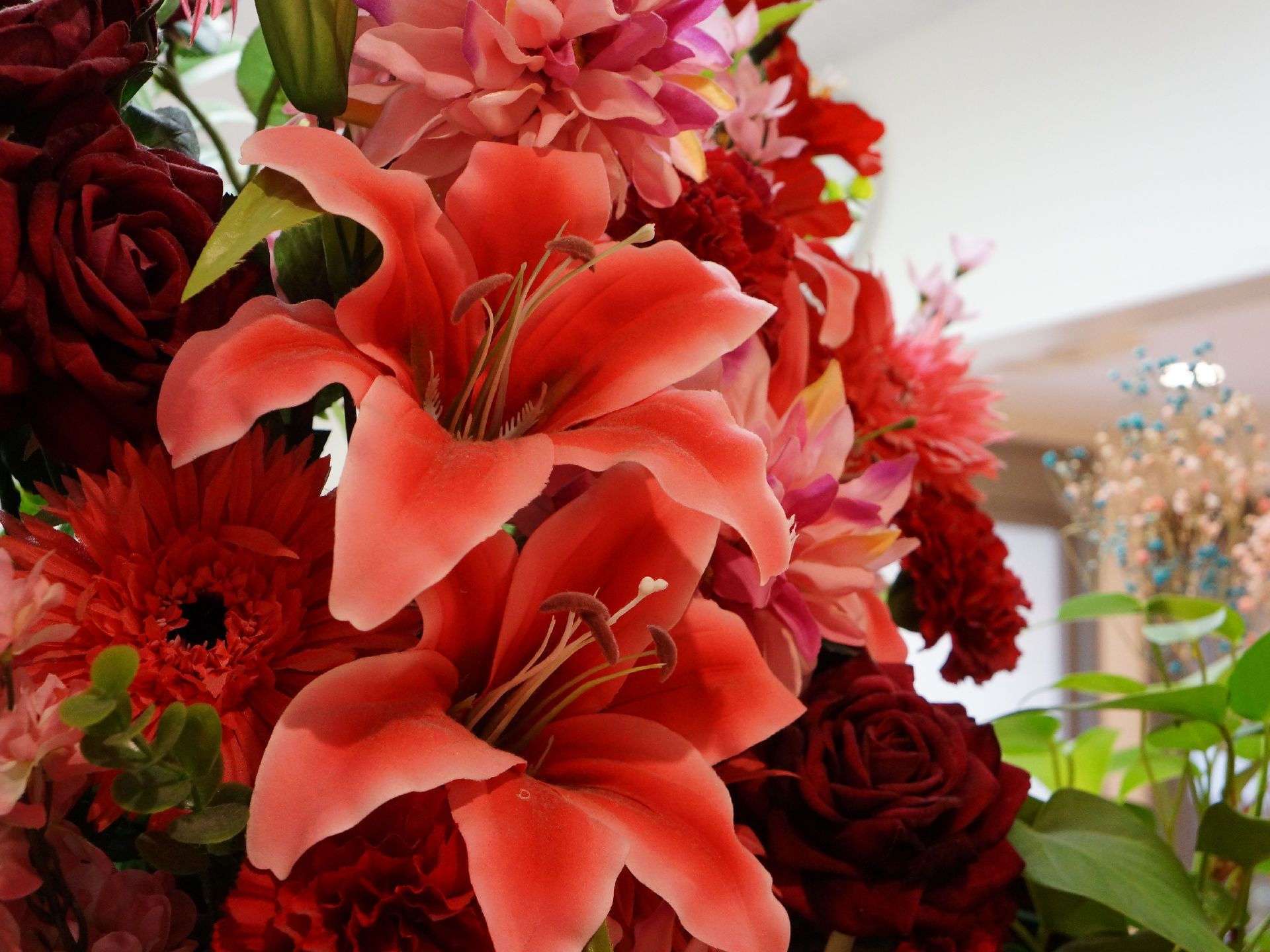 花びんに活けられた花は、赤やピンクの大きな花が中心で、バラやゆり、カーネーションなどがあり、とてもきれいな花である。