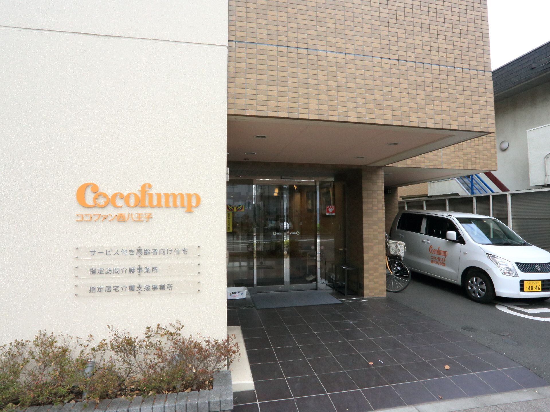 施設の出入り口の白壁にはオレンジ色で施設名とロゴが書かれている。その下には施設の簡単な説明もあり判りやすい。入り口は自動ドアになっている。