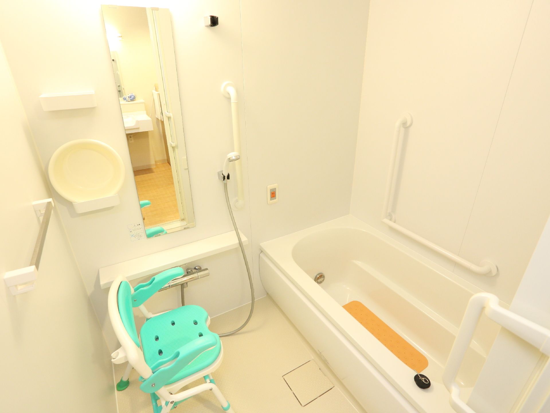 浴室は白を基調としていて追い焚き機能が付いた高齢者用の浴槽が設置されている。壁には手すりと呼び出しスイッチがあり、椅子が置かれている。
