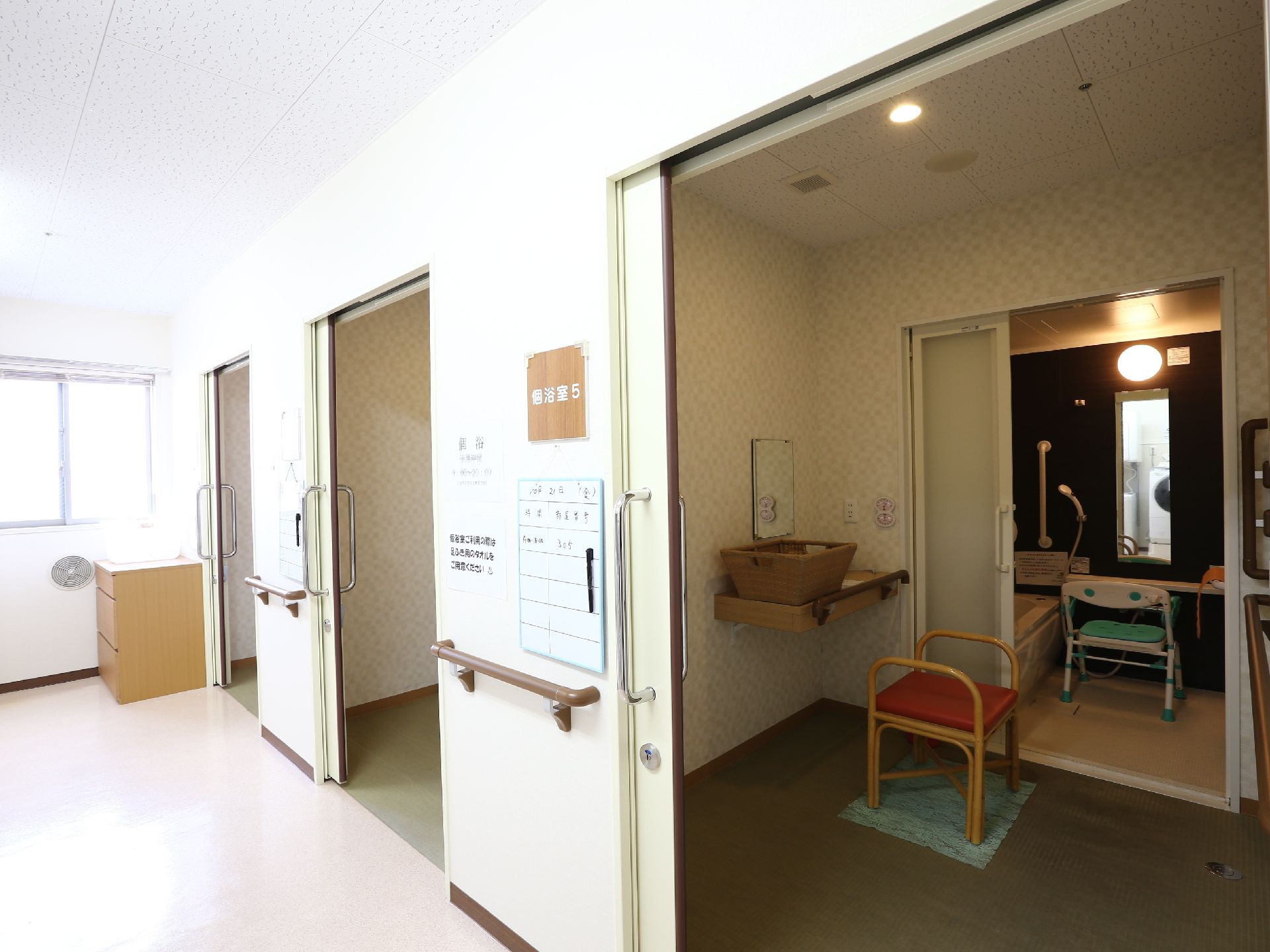 施設には共同の浴室が複数設置されている。写真には浴室5と書かれたパネルが写っている。脱衣所は広く車椅子でもしそのまま入ることができる。