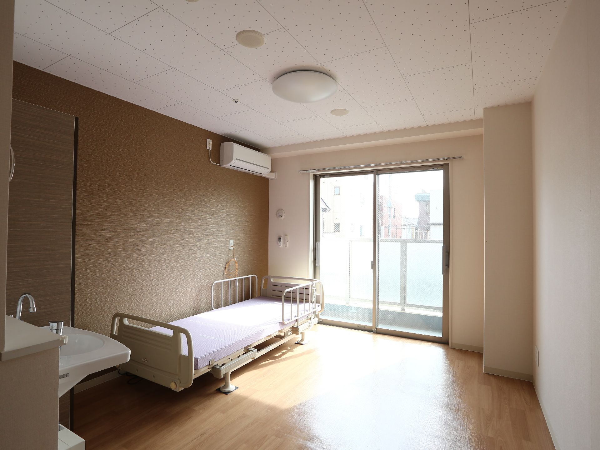 広々とした居室には大きな窓が取り付けられている。また壁にはエアコンがあり、照明器具も備え付けられている。