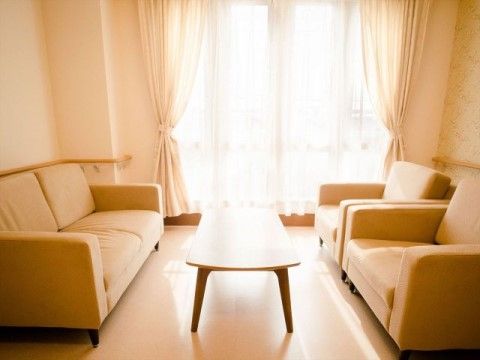 大きな窓があり日が差し込む明るい空間に、ソファーとテーブルが置いてある。壁にはすべて手すりが付いている。