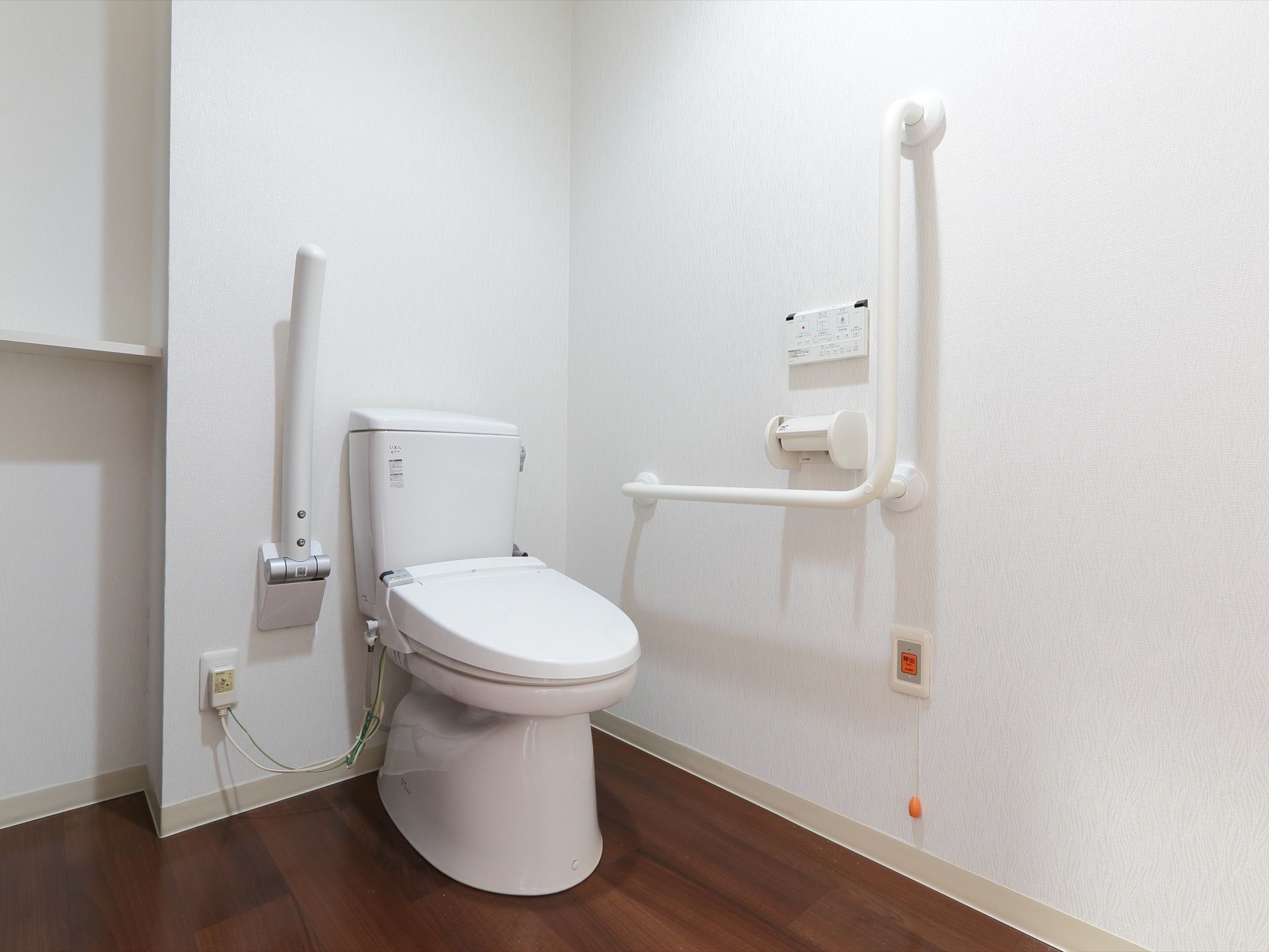 全て白で統一されたトイレは、可動式手すり、壁にはL字型の手すり、緊急時コールボタンが設置されている。