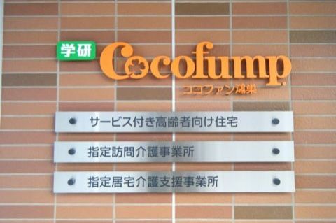 茶色系のレンガの壁にオレンジの文字で書かれている施設名の看板