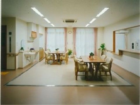 テーブル、手すり付きの椅子が、広いスペースの中に余裕をもって置かれている。壁と天井の色は白色基調で、エアコン、照明設備が設置されている。