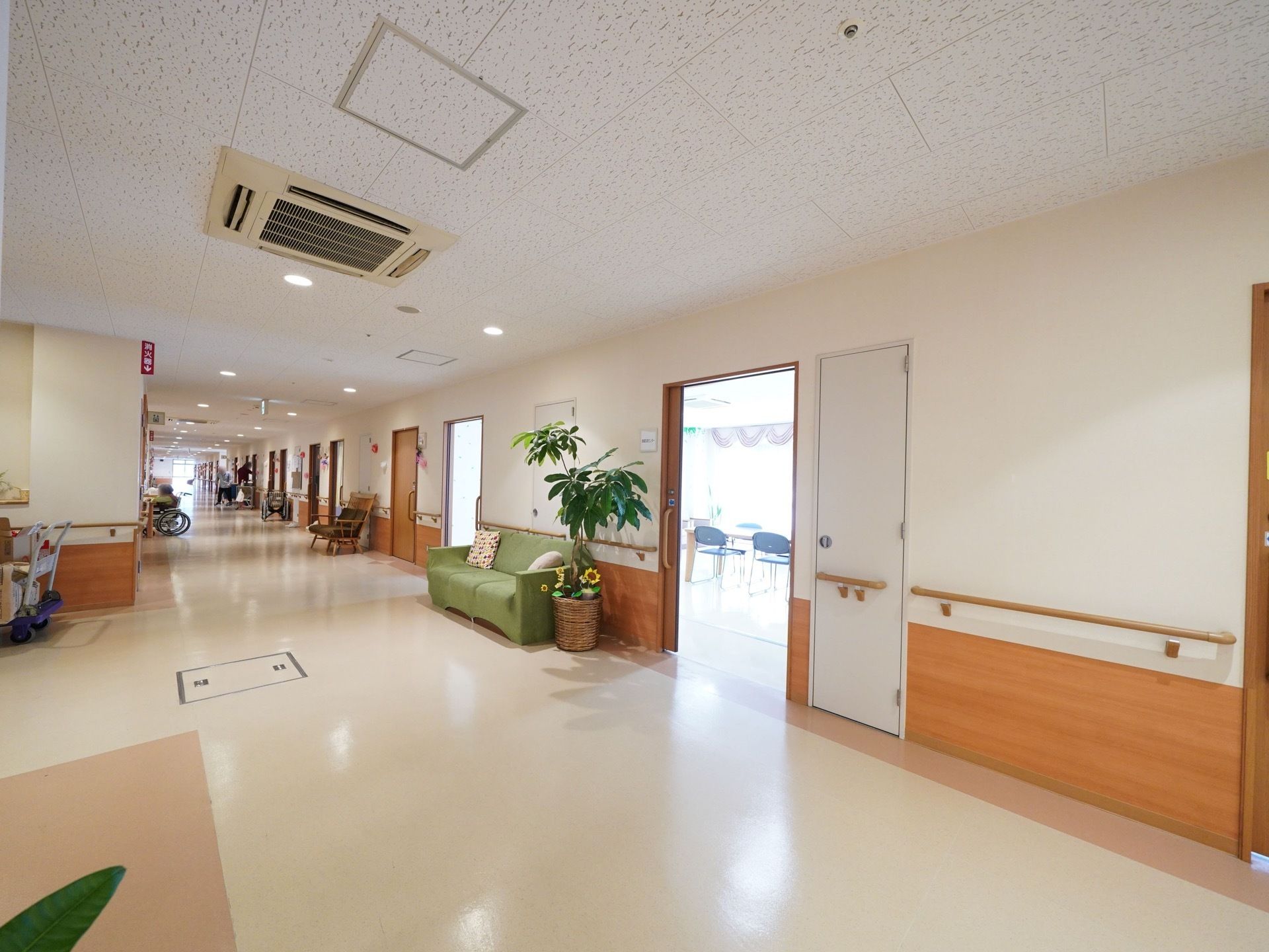 居室や共有スペース前の廊下は広く、車椅子２台通っても余裕がある。廊下の各所にソファや椅子があり、入居者様同士の交流の場になっている。