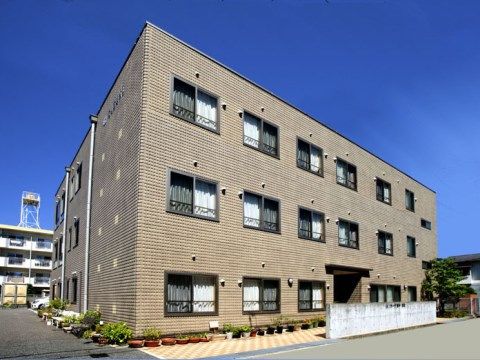 青空の下に建つ、窓が等間隔に並んでいる３階建ての施設