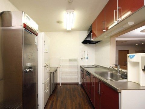 壁際に業務用と家庭用の冷蔵庫、作業台が並んでいる。通路を挟んで流しとIH台が並び、カウンターがある。