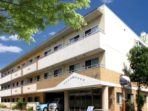 １階部分に２台の乗用車が停まっている３階建ての建物