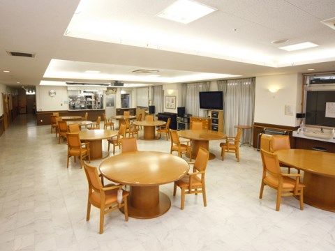 白い天井と床の室内には、円や楕円のテーブルが置かれている。食事をしたり、テレビを楽しんだりできる空間である。