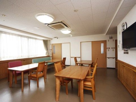 壁掛けテレビが設置されており、テーブルセットが４つある。窓からはやわらかな日差しが注ぎ込んでおり、ゆっくりテレビ鑑賞が楽しめる。