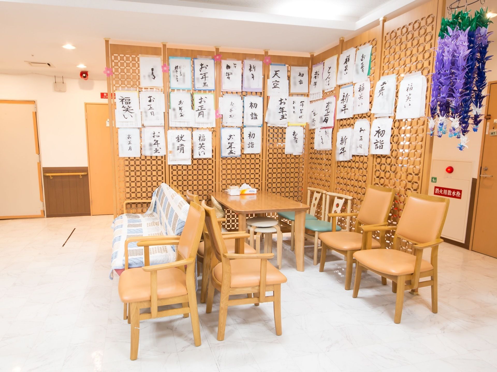 天井から床までパーテーションが設置されており、習字の作品が多数展示されている。その隣には、千羽鶴が飾られている。