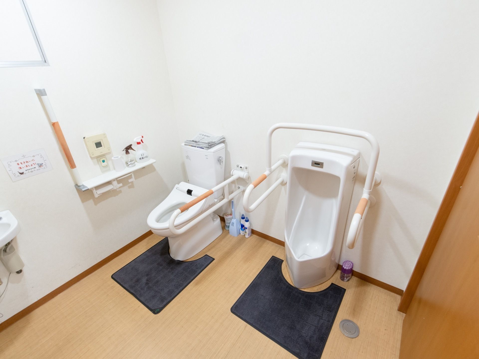 共用トイレの室内。広い造りになっており、男子用小便器のとなりに大便器が設けてある。ともに車椅子用の手すりがある。