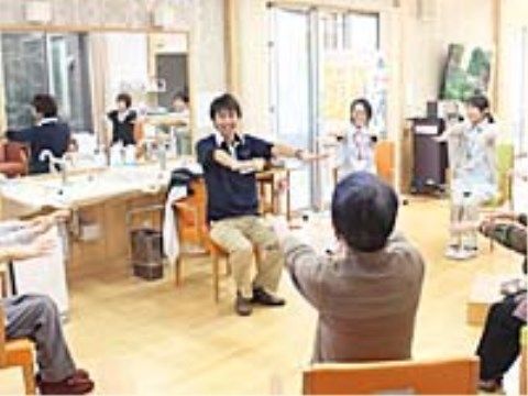 円形に並べられた椅子に座って、体操をしているスタッフと入居者様