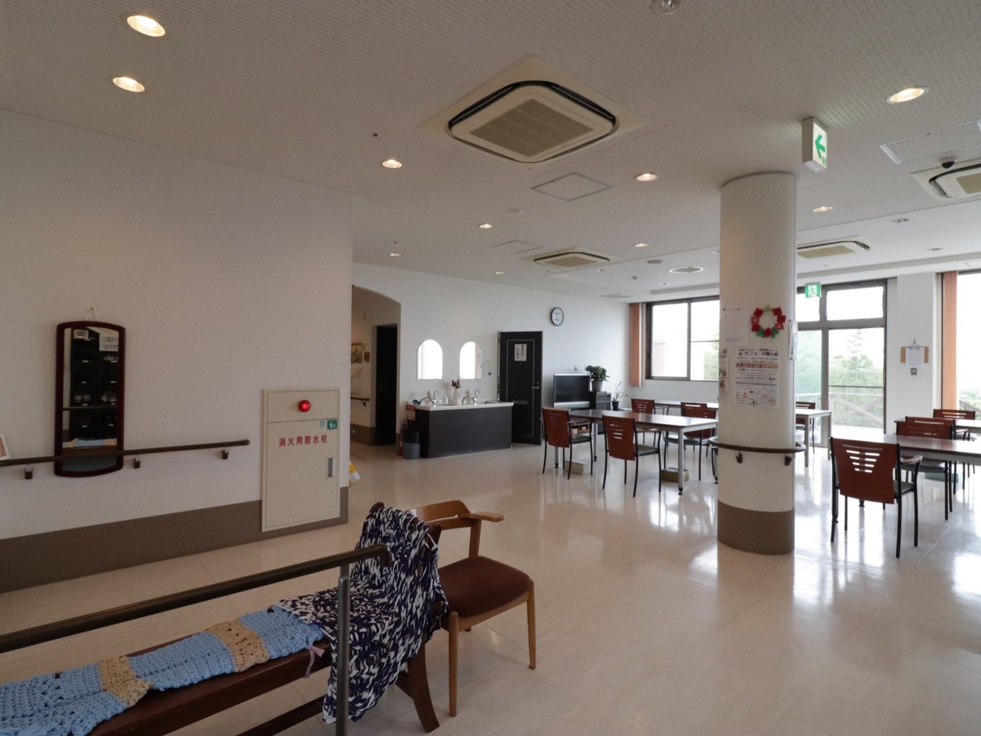 消火用散水栓が備わった火災報知ボタンが壁に設置されている。天井や窓には避難誘導灯が取り付けられている。