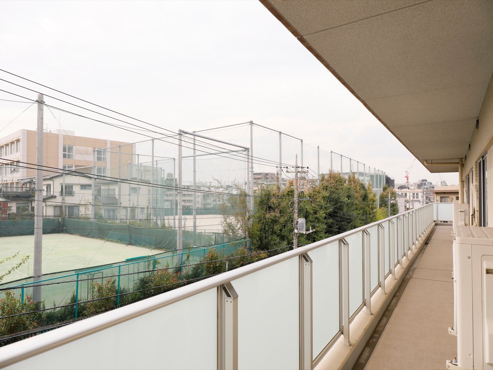仕切りのないベランダが施設の端まで続いている。プライバシー保護のため、フェンスには外側から見えにくい材質が用いられている。