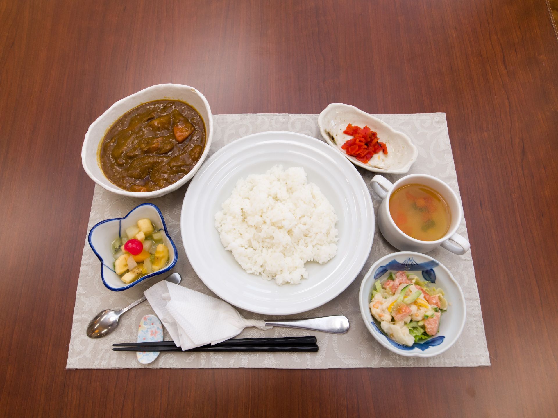 カレーライス定食になっており、ライス、カレー、福神漬け、サラダ、スープ、お箸、スプーンが用意されている。