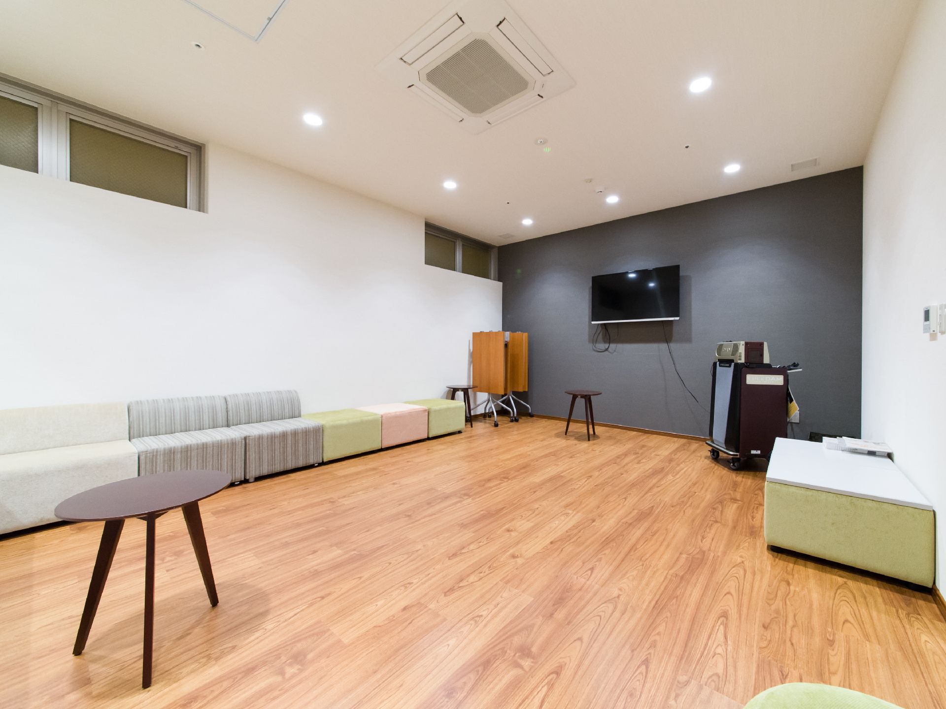 壁際にカラオケの映像を映し出す大きなテレビ画面が設置されていて、椅子が一列に並んで設置されている。テーブルもある。