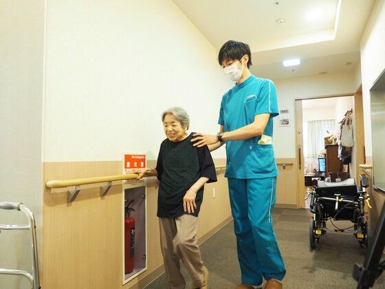 笑顔のおばあさんとスタッフ廊下