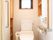 ウオッシュレット式トイレの左手奥には木製の棚になっている。右側の棚は壁に埋め込まれており各種スイッチや手すりもついている。