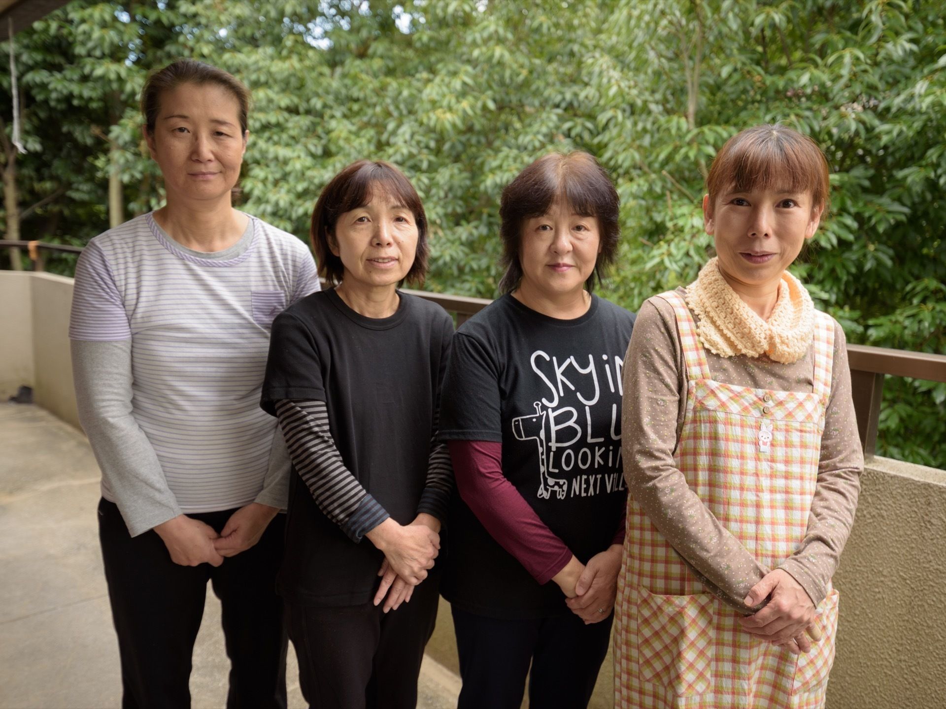 背景に木々が広がるベランダに並んで立っている、女性スタッフ４名