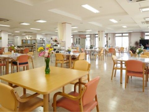 木目調のテーブルセットが、ゆとりあるスペース配分で配備された食堂である。窓やテレビが設置されている。