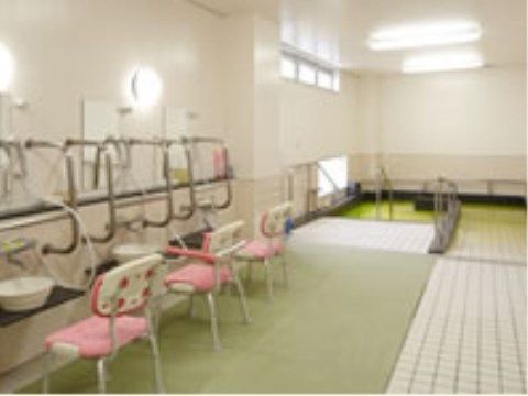 共用の浴室には入浴用の椅子が洗い場に設置してあり、入居者様は楽な姿勢で体を洗うことができる。壁にはいたるところに手すりが取り付けられている。