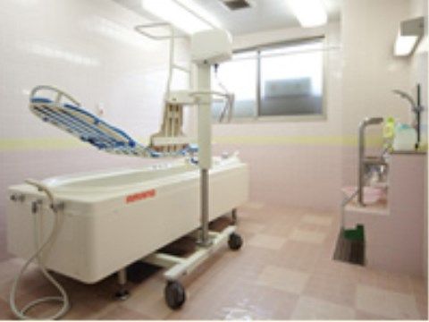 電動式のリフト付き特殊介助浴槽がある。横になったまま移動し入浴する。タイル張りの室内は窓があり明るい。