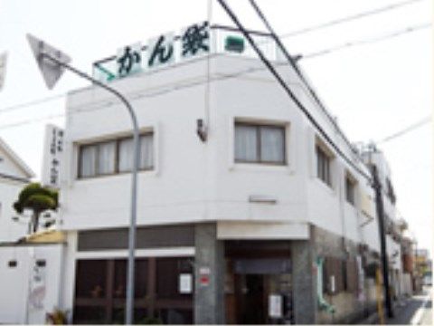 ２階建てで白い外観の建物がある。屋上もあり、屋上には柵が設置されている。柵にはお店の名前が書かれている。