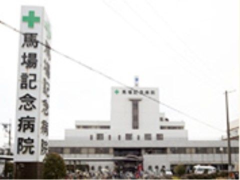 白い外観の病院がある。大きな立方体の看板にはミドリ十字マークがあり、その下には病院名が大きく書かれている。