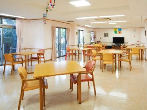 広い部屋の突き当りにはテレビが置いてある。左側には掃き出し窓が並んでおり、ダイニングセットが間を空けて並んでいる。