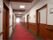 中央が赤く、両端がグレーの絨毯敷きの廊下が続いている。両側には居室ドアが並び、壁には手すりが付いている。