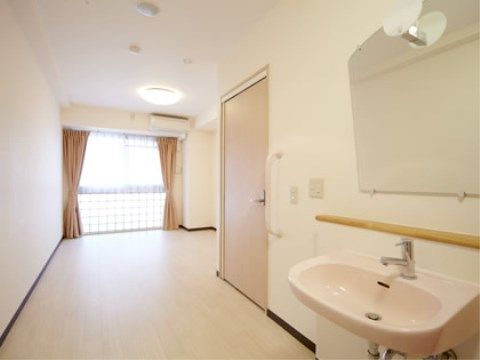居室には鏡が取り付けられた洗面台が設置されている。鏡は大きいので姿を見やすくなっている。室内も広々としている。