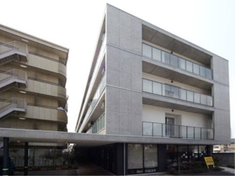 打ちっぱなしのコンクリートが現代的な4階建ての建物。1階部分には大きなひさしがあり、雨の日にも濡れずに歩ける。