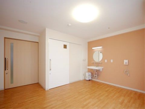 すりガラスの細長い窓が付いた引き戸のある居室は、優しい色調でリラックスできる雰囲気である。室内には洗面台も設置されている。