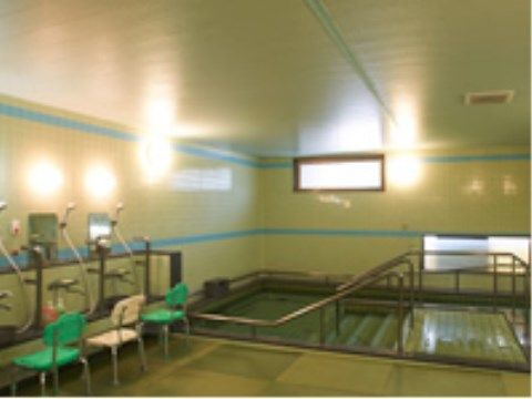 タイル張りの浴室にしっかりとした手すりのついた洗い場が並ぶ。洗い場には背もたれつきの浴用イスが置かれている。浴槽の周りにも手すりが多い。