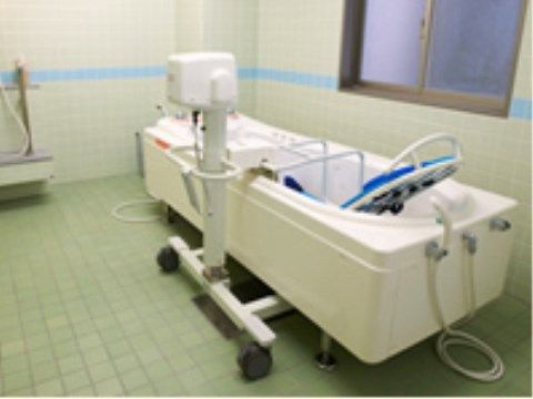 タイル張りの部屋の隅に、寝たままの姿勢でも入浴できる介護用の浴槽が置かれている。壁には曇りガラスの窓がある。