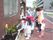幼稚園の子どもたちと入居者様が一緒になって花壇に花を植えている。入居者様が子どもに花の植え方を教えている。