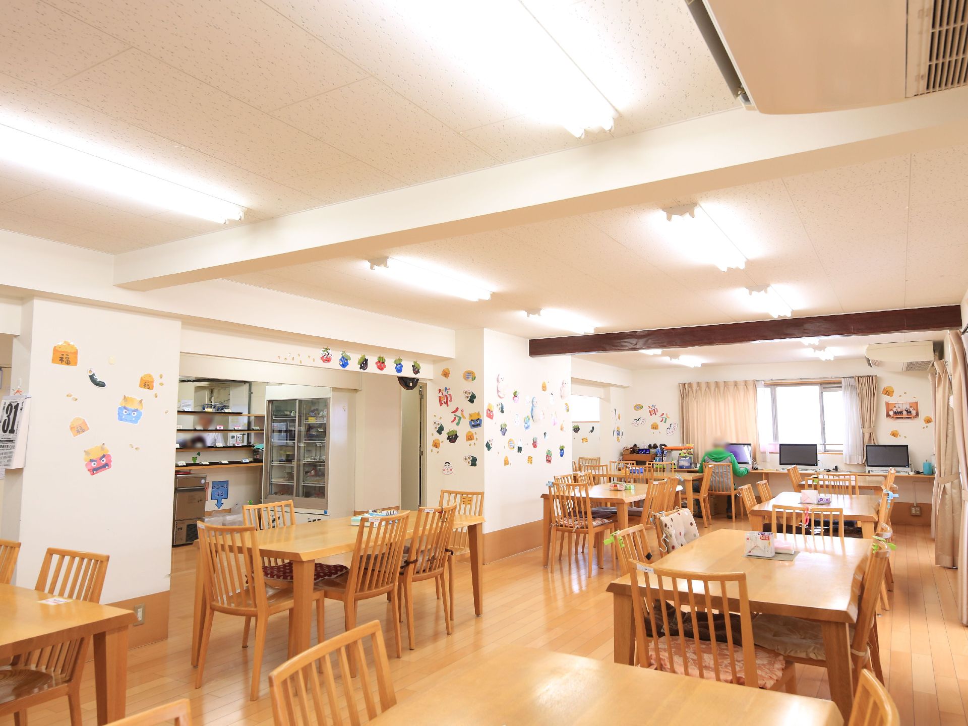 入居者様が集まるダイニングは広いスペースとなっている。すぐ横にはキッチンが併設されている。飾りが施された明るい場所である。
