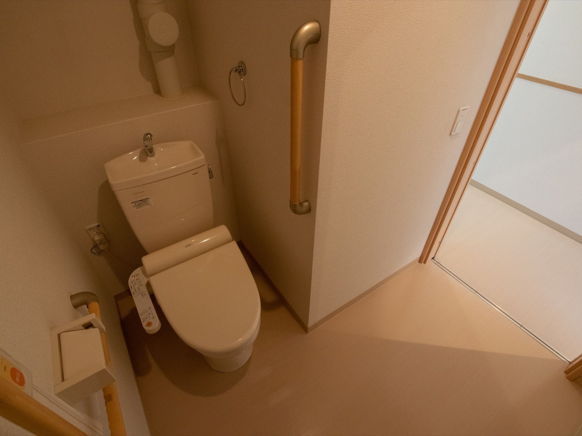 居室内のトイレである。両側の壁に手すりが備わっており、手洗い水が出るそばにはタオルをかけることができる。