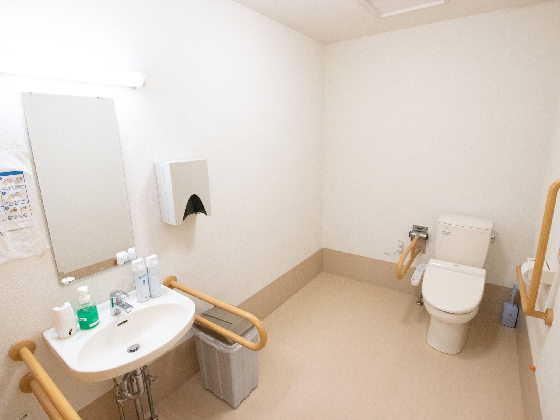 広々としたスペースが確保されているトイレである。左端には洗面台があり、蛇口の横に消臭スプレーやハンドソープなどが置いてある。