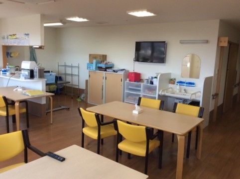 「介護付有料老人ホーム あんしん館」の談話室。角の丸いテーブルと黄色い椅子が、入居者様に使いやすい家具になっている。