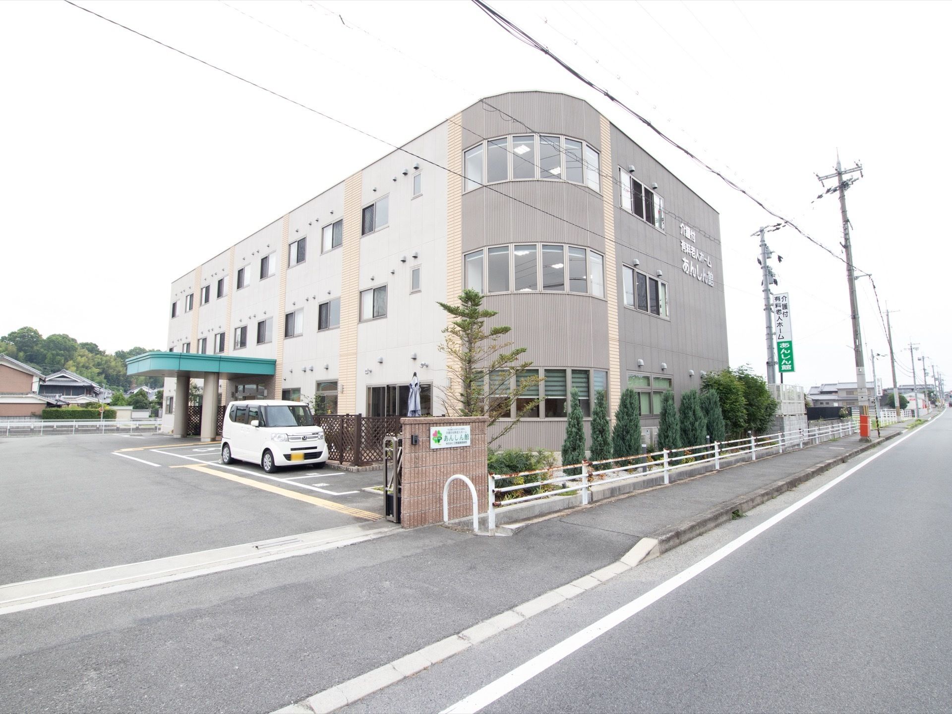 グレーを基調とした３階建ての建物である。モダンな雰囲気がある。玄関前に大きなひさしがついており、その前には広い駐車スペースがある。